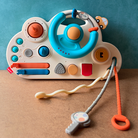 Volante sensorial para niños, con botones de colores y accesorios para jugar.