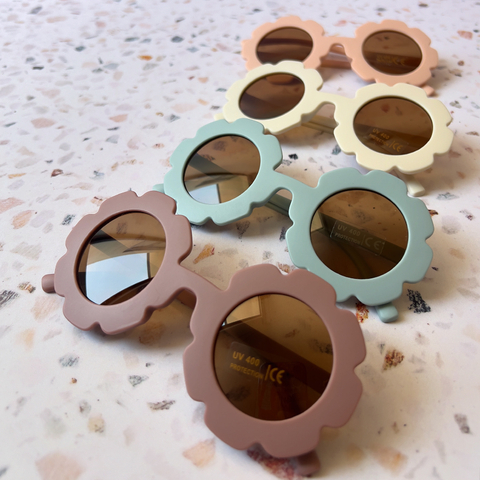 Lentes de sol de diseño floral en varios colores sobre una superficie de piedra.