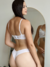 Modelo vestindo um conjunto sem bojo e com aro em tule e renda na cor branca, exibindo a parte de trás do produto.