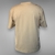 Camiseta Monastery en tono beige, perfecta para un estilo sobrio y sofisticado. Destaca por su diseño con la palabra "MONASTERY" en letras grandes y un escudo central con las iniciales "STM" enmarcadas por hojas de laurel, ofreciendo un look versátil y at