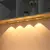 Imagem de uma luz de LED com sensor de movimento instalada em uma prateleira, emitindo um brilho suave na parede.