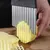 Cortador de fritas ondulada cortando uma batata na tábua de cozinha.