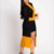 Cardigan longo em preto e amarelo com detalhe na frente, usado por uma mulher em pé.