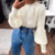 Blusa de inverno branca com detalhes de tricot e mangas bufantes, combinada com jeans de cintura alta.