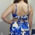 Vista traseira do vestido curto Farm, com detalhes em azul floral, destacando o laço na parte de trás.