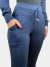 Foto em close da parte superior de uma mulher, levemente lateralizada, vestindo uma calça azul marinho em tecido sport fleece. A imagem destaca os detalhes do cós alto com cordão, bolsos frontais e a textura do tecido.