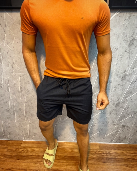 Modelo vestindo shorts de linho premium na cor Preto, com camiseta Telha e chinelos.
