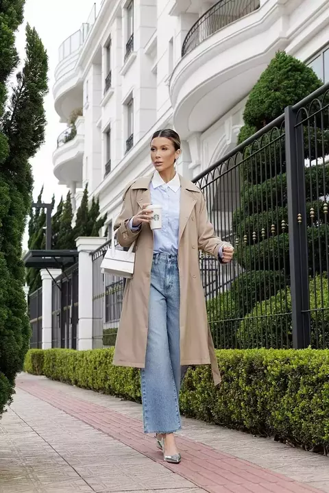Sobretudo com comprimento midi, apresenta um design clássico de trench coat, com gola, lapelas e uma faixa para amarração na cintura. As mangas são longas e levemente soltas. Tecido estruturado, com um caimento elegante.