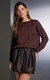 Mulher vestindo blusa de tricot marrom com bordado de plumas e saia preta brilhante