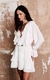 A imagem apresenta a modelo vestindo um vestido offf-white curto de babados boho.