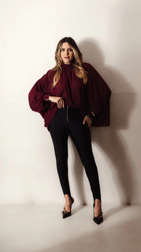 Blusa em crepe leve e fluido com modelagem ampla para um caimento elegante e confortável. Apresenta gola dobrada clássica, delicados franzidos nos ombros que adicionam um toque de sofisticação e punhos que valorizam o visual. Confeccionada em 100% poliést