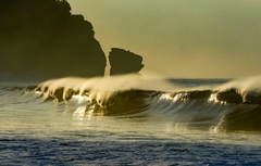 Série de ondas perfeitas quebra ao entardecer em El Salvador, com spray dourado e falésias ao fundo criando uma cena mágica de fim de tarde no Pacífico.
