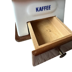 Detalhe da gaveta em madeira do moedor 'Kaffee', mostrando o interior onde os grãos moídos são armazenados com charme artesanal.