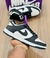 Tenis Nike Dunk Panda em preto e branco, segurado por uma mão. A caixa do produto está ao fundo.