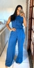 Mulher sorridente vestindo conjunto social de linho azul com calça pantalona e camisa sem mangas com botões, tirando selfie em espelho dentro de casa