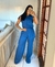 Mulher sorrindo em um conjunto social de linho azul, posando em frente ao espelho em um ambiente interno.