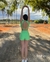 Mulher posando ao ar livre, vestindo um conjunto verde com short e top, em um cenário natural com árvores ao fundo.