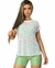 Modelo usando uma blusa em tela branca, com shorts verdes, ideal para looks descontraídos.