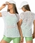 Modelo usando blusa em tela ampla carol, combinada com short verde e boné branco.