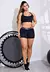 Mulher usando conjunto fitness preto com short curto e cropped, posando de costas com uma perna levantada