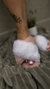 Chinelo de pelúcia com pelo branco e base off white usado no pé de mulher com tatuagem floral e tornozeleira