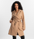 Mulher usando o Trench Coat Essencial bege da MR & Co., modelo atemporal e sofisticado com faixa para ajuste e caimento fluido. Confeccionado em moletom felpado de menor impacto, combina conforto térmico com design minimalista e sustentável.