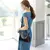 Modelo feminina vestindo branco e usando bolsa hobo preta no ombro, destacando o estilo casual e a alça longa transversal ajustada.