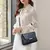 mulher vestindo look casual e elegante com bolsa tote azul escuro no ombro através da alça transversal, demonstrando proporção média e caimento estruturado junto ao corpo.