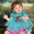 Bebê Reborn Abigail sorrindo, com cabelinho fio a fio, olhos delicados e expressão fofa de felicidade. Boneca realista com detalhes incríveis.