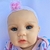 A Bebê Reborn April encanta com seu rostinho alegre e expressão doce, que transmite a pureza e a alegria de um verdadeiro bebê.