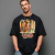 Homem usando camiseta preta oversized unissex com estampa tropical de cachorros engraçados com frase divertida good vibes