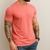 Homem usando camiseta básica gola redonda na cor rose com tatuagens nos braços