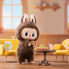 alt="Labubu Macaron disfraz de conejo marrón tomando café con postre"