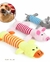 Pelúcia para pets em forma de animais coloridos com corpo listrado, incluindo pato amarelo, porco rosa e rato cinza, e um cachorro segurando um brinquedo de pelúcia na boca.