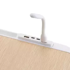Detalle de conexiones USB y lámpara flexible blanca integrada en mesa con superficie de madera clara
