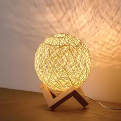 Lámpara de mesa Lumi Esfera Habitat con diseño esférico tejido y luz cálida sobre base de madera