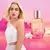 Perfume Autenti-k by me de Cyzone con frasco rosa y mujer rubia con vestido blanco sobre fondo rosa