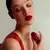Mujer con vestido rojo aplicándose perfume JoyceLove Potion Cherry con frasco rojo