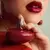 Mujer con labios rojos sosteniendo un frasco rojo de perfume JoyceLove Potion Cherry de 50 ml