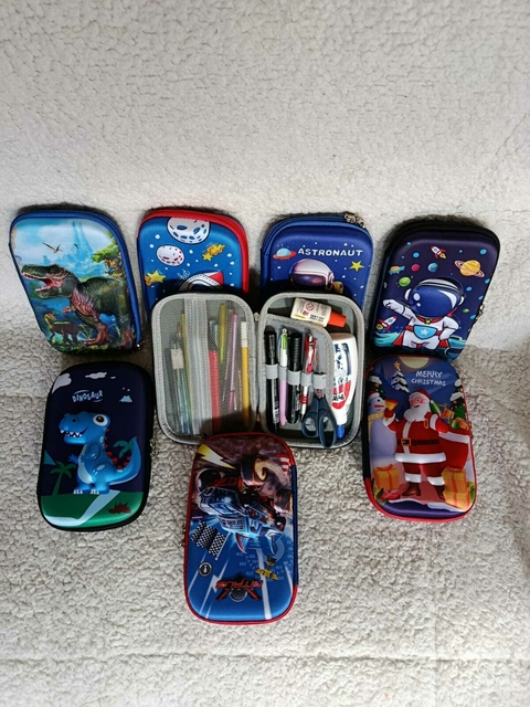 Estojo escolar infantil rígido com estampa 3D, divertido e resistente. Modelos de dinossauro, astronauta, espaço, carro e Natal. Possui divisórias internas, zíper reforçado e espaço para lápis, canetas, tesoura e outros materiais escolares.