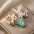 Broche em formato de flor com pérolas e detalhes delicados. Design elegante da Wuli & Baby, ideal para uso feminino ou unissex em festas escritório.