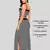 Modelo luciendo un conjunto femenino de dos piezas en piel de durazno color negro con rayas blancas, compuesto por un crop top de tiras delgadas y una falda larga ajustada con abertura lateral, combinado con zapatillas urbanas.