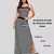 Modelo luciendo un conjunto femenino de dos piezas en piel de durazno color negro con rayas blancas, compuesto por un crop top de tiras delgadas y una falda larga ajustada con abertura lateral, combinado con zapatillas urbanas.