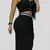 Mujer luciendo un conjunto de falda y crop top negro en tela suplex, con botones decorativos y abertura lateral, posando en un espacio interior moderno. El conjunto resalta su figura y combina estilo, comodidad y elegancia casual.