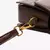 Detalhe do fecho metálico dourado da alça removível de bolsa feminina marrom em couro sintético, com costura reforçada e acabamento de alta qualidade.