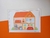 Ilustração de uma casa em miniatura com móveis, incluindo sofá, cama, cozinha e banheiro.