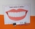 Imagem de um cartaz com um sorriso mostrando dentes brancos e saudáveis, acompanhado de uma escova de dentes e um marcador, com a frase "Vamos escovar os dentes!"