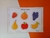 Imagem de um jogo de pareamento de frutas, com ilustrações coloridas de morango, laranja, uva, pera, maçã e banana sobre um fundo laranja.