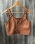 Top corto marrón tipo corset con detalle de cordones frontales colgado en percha de madera