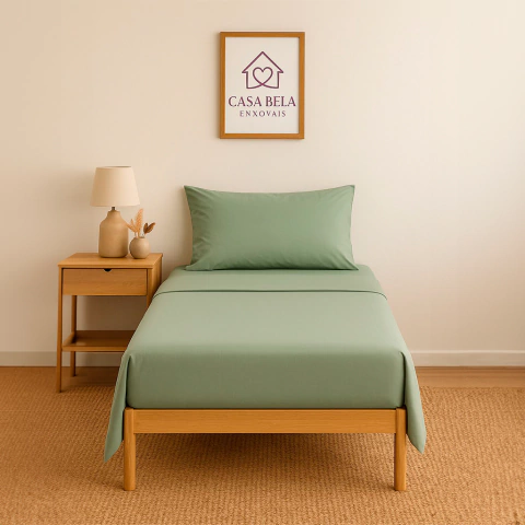 Lençol de malha verde com elástico em cama solteiro com travesseiro combinando, ao lado mesa de cabeceira de madeira com abajur e vaso decorativo